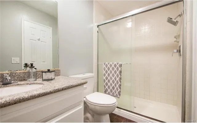 a bathroom with a granite countertop sink toilet and shower