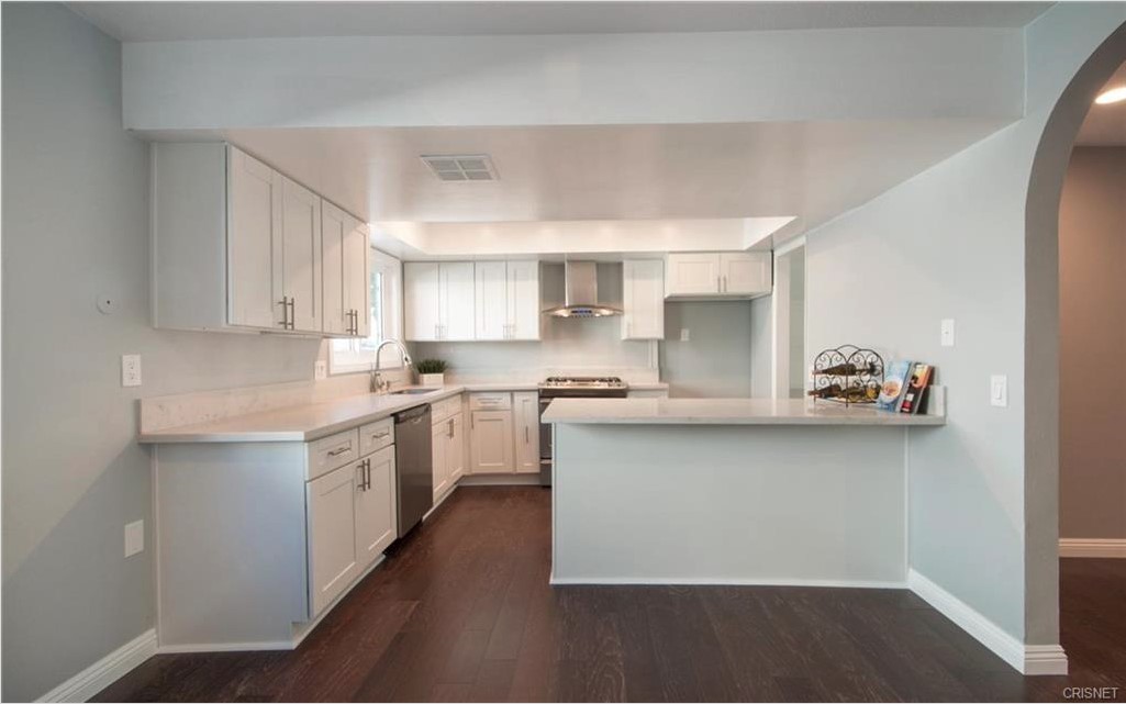 17824 Killion Street Encino, CA 91316 - Photo 7 of 25 a kitchen with stainless steel appliances a sink dishwasher a refrigerator and white cabinets with wooden floor