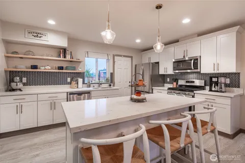 a kitchen with stainless steel appliances granite countertop a stove top oven a refrigerator a sink and white cabinets