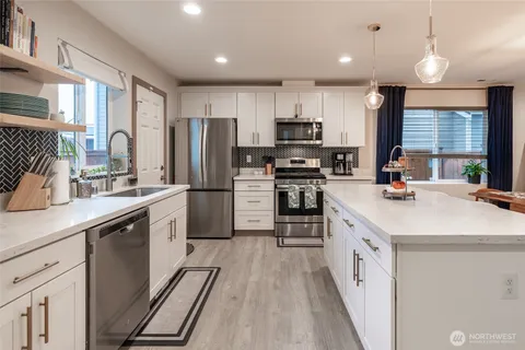 a kitchen with stainless steel appliances a sink stove refrigerator and cabinets