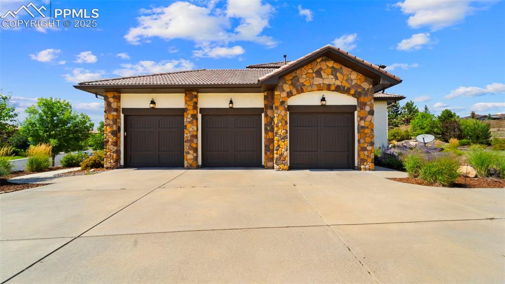 13625 Random Ridge View Colorado Springs, CO 80921 - Photo 39 of 50 Mediterranean / spanish home with concrete driveway, stone siding, a garage, a tiled roof, and stucco siding