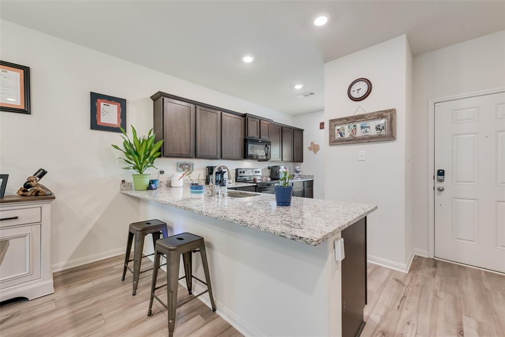 159 Bush Drive Venus, TX 76084 - Photo 9 of 24 a kitchen with stainless steel appliances granite countertop a refrigerator a stove a sink dishwasher and microwave with wooden floor