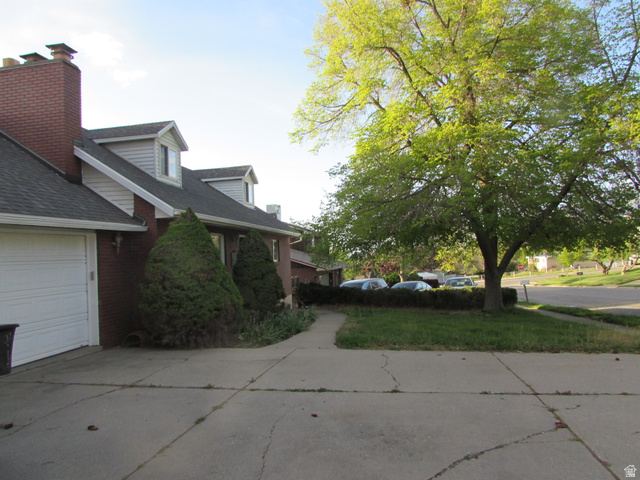 3166 Linden Street Bountiful, UT 84010 - Photo 24 of 25 View of side of property with brick siding, a shingled roof, driveway, a lawn, and a garage