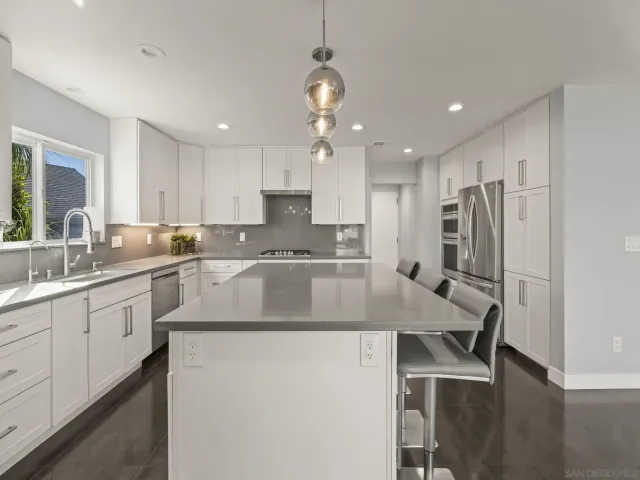 a kitchen with stainless steel appliances granite countertop a sink a stove a dining table and chairs