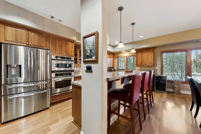 a kitchen with stainless steel appliances a refrigerator a stove top oven a dining table and chairs