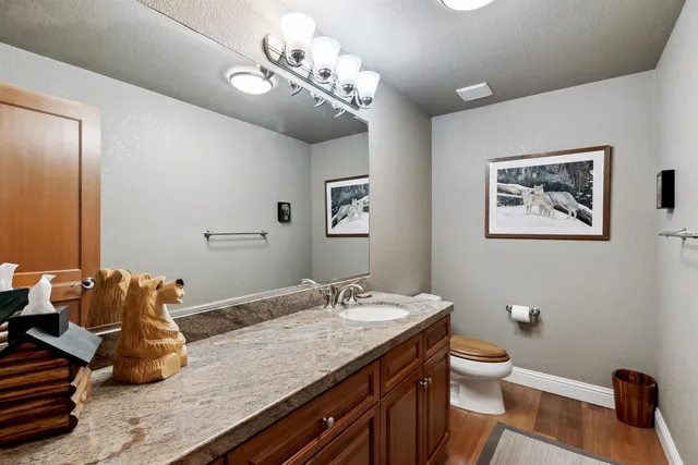 a bathroom with a granite countertop sink a toilet and mirror