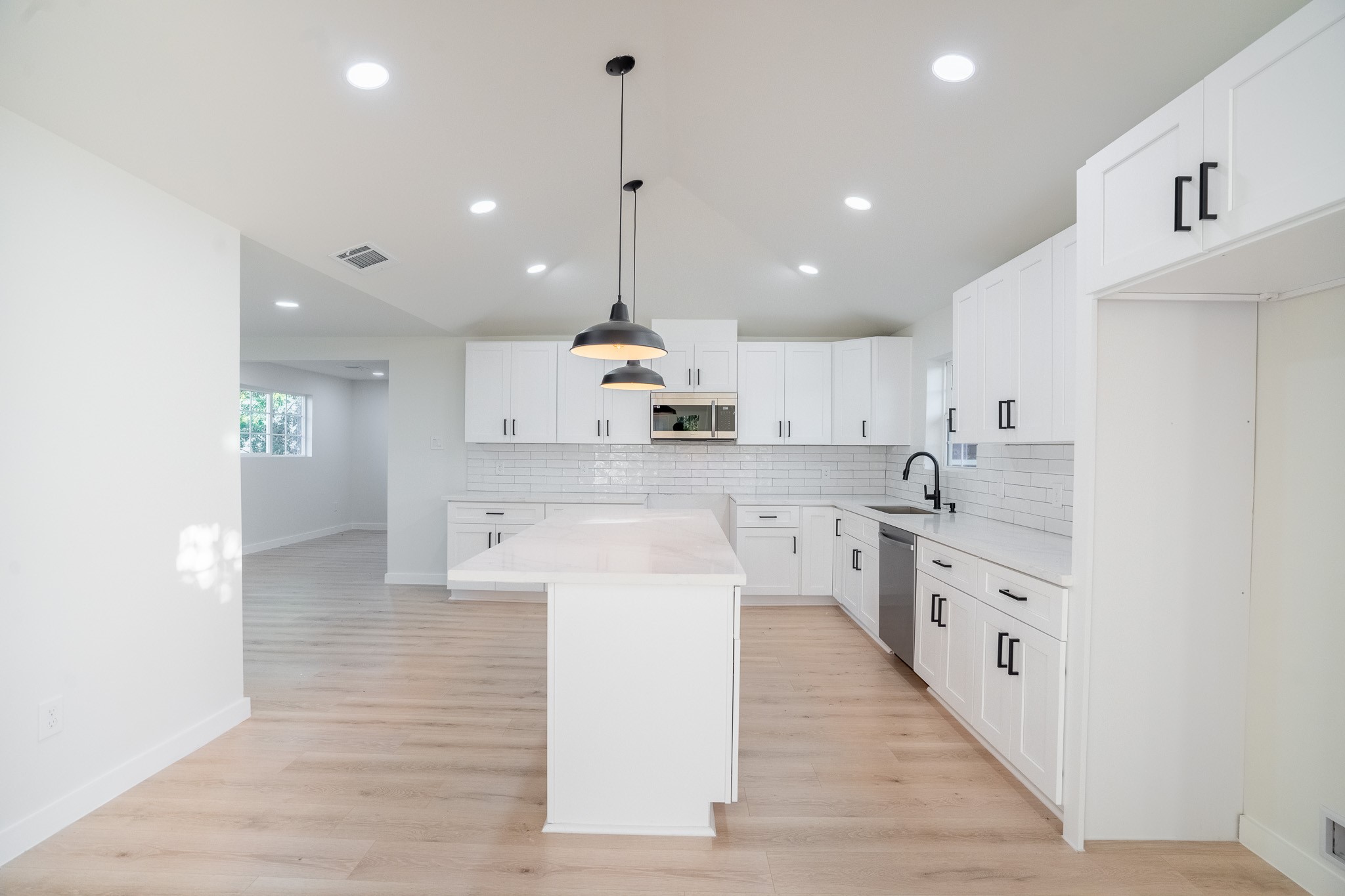 1310 East 34th Street Houston, TX 77022 - Photo 1 of 19 a large kitchen with stainless steel appliances kitchen island a stove a sink a refrigerator and white cabinets with wooden floor