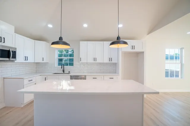 a kitchen with kitchen island a center island a sink cabinets and wooden floor