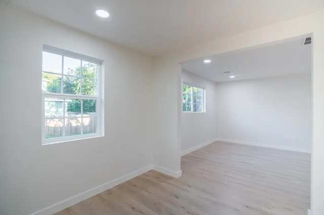 an empty room with wooden floor and windows