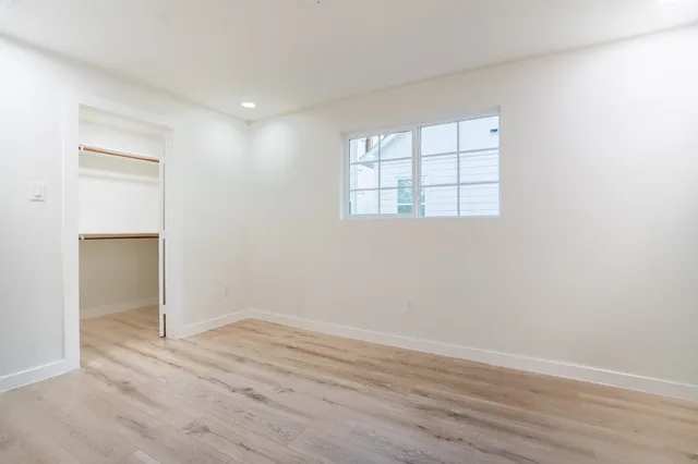 an empty room with wooden floor and windows