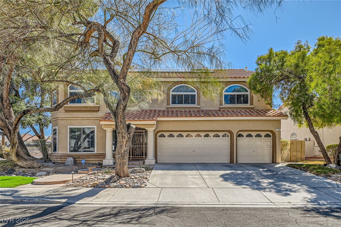 View of front facade with stucco siding, a tiled roof, concrete driveway, and a garage