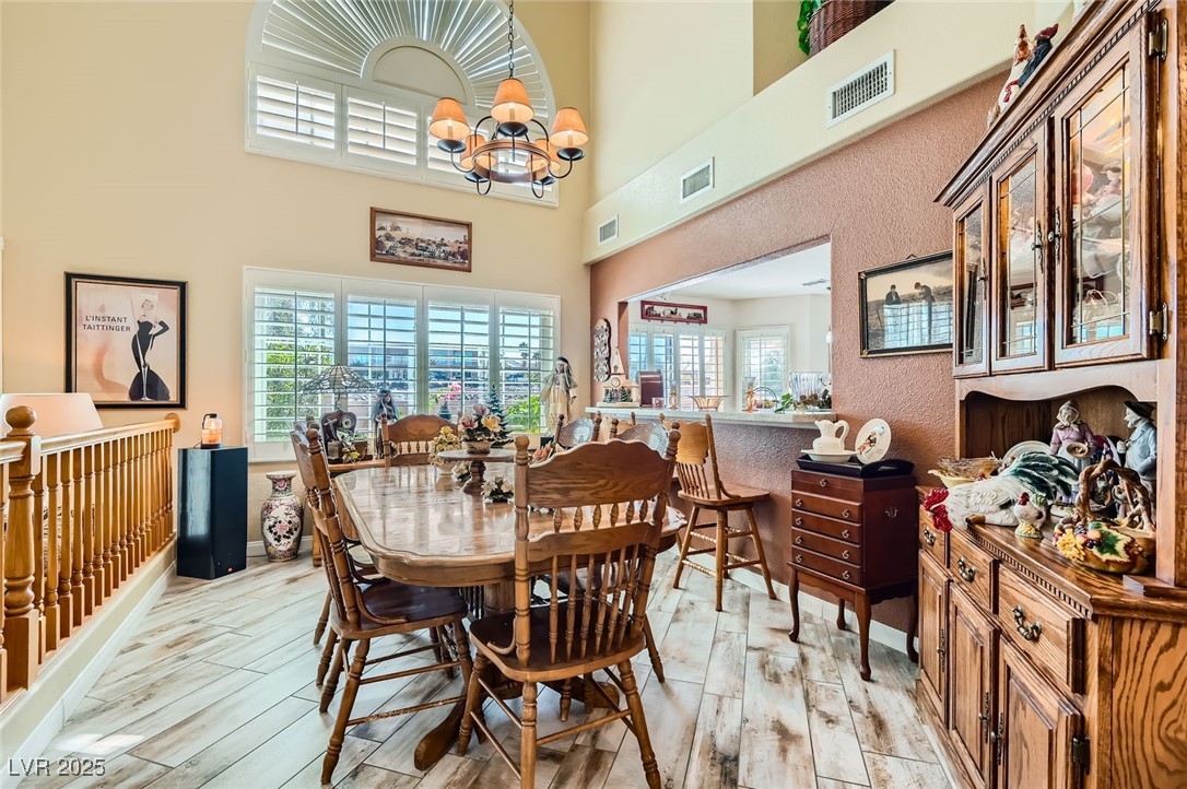 20 High Sierra Henderson, NV 89074 - Photo 14 of 53 Dining area featuring wood finish floors, visible vents, a notable chandelier, and a high ceiling