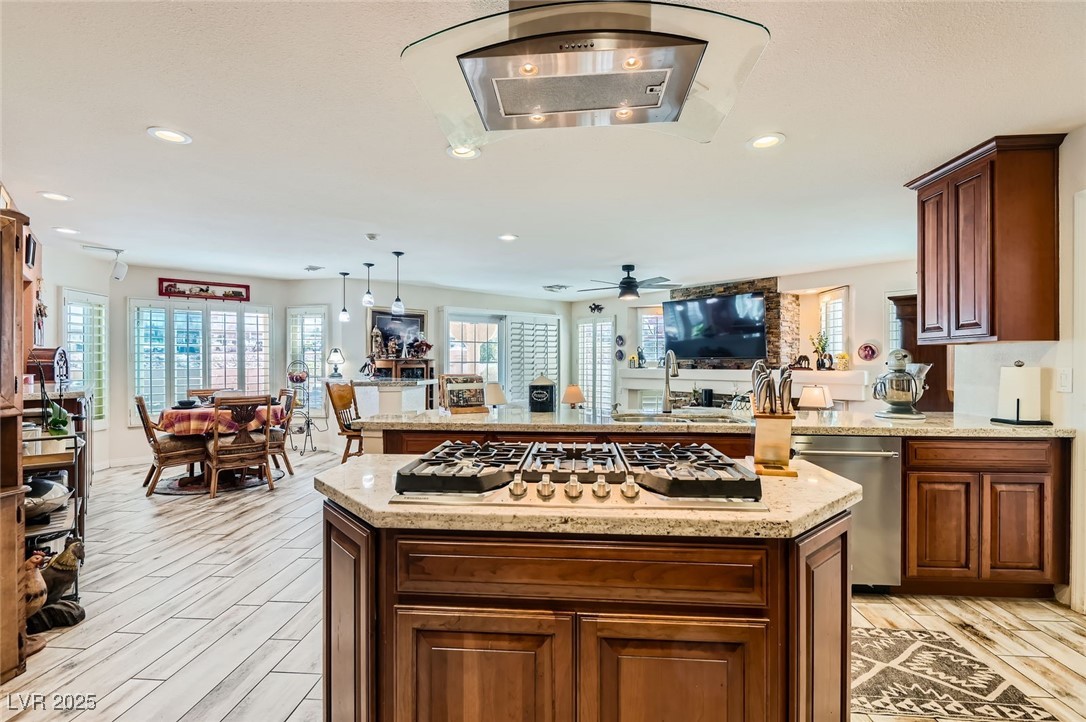 20 High Sierra Henderson, NV 89074 - Photo 21 of 53 Kitchen with light stone countertops, a ceiling fan, light wood-style flooring, appliances with stainless steel finishes, and a center island