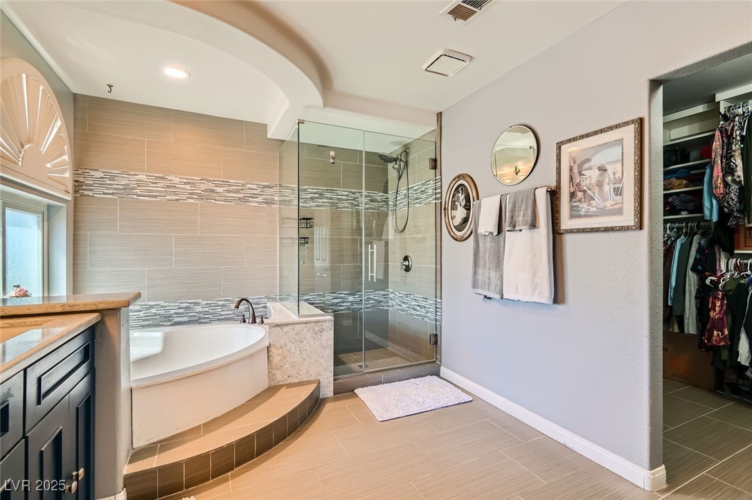 20 High Sierra Henderson, NV 89074 - Photo 34 of 53 Bathroom featuring visible vents, a walk in closet, a garden tub, a stall shower, and vanity