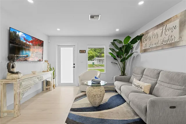 a living room with furniture a flat screen tv and a chandelier