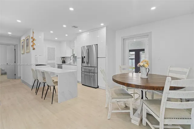 a kitchen with kitchen island a dining table chairs stainless steel appliances and cabinets