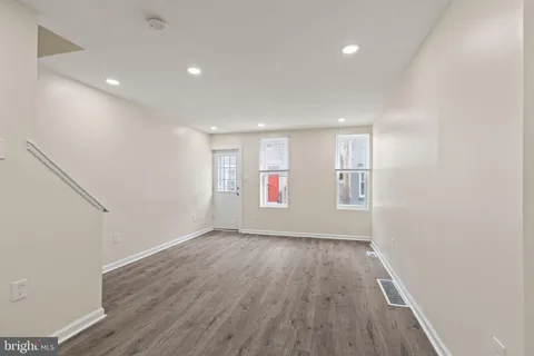 an empty room with wooden floor and windows