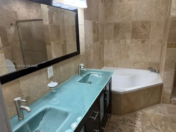 a bathroom with a granite countertop sink a mirror and shower