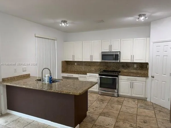 a kitchen with granite countertop a stove top oven sink and cabinets