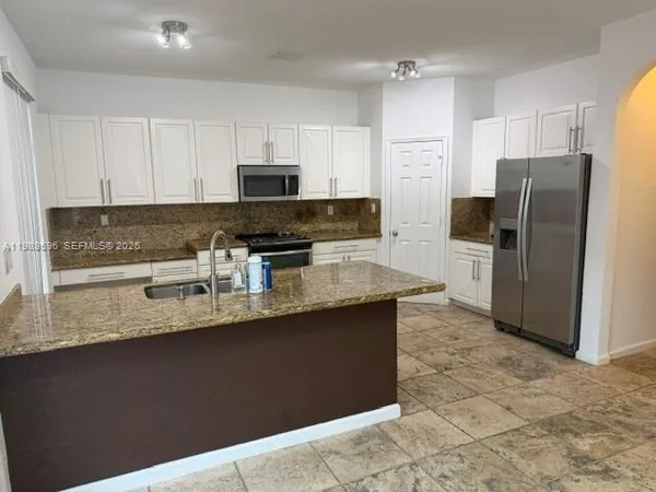 a kitchen with stainless steel appliances granite countertop a sink a stove a refrigerator a microwave and cabinets
