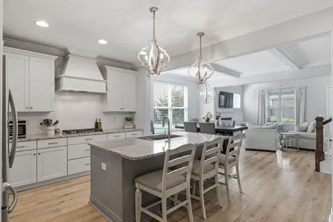 a kitchen with stainless steel appliances granite countertop a dining table chairs stove and white cabinets