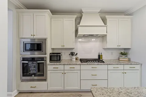 a kitchen with stainless steel appliances granite countertop white cabinets and a stove