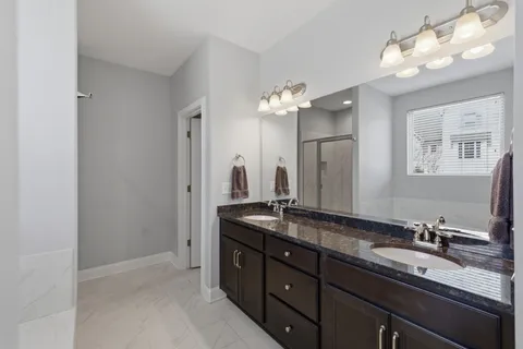 a bathroom with a granite countertop double vanity sink and a mirror