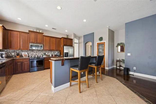 a kitchen with stainless steel appliances granite countertop a sink a stove a refrigerator and a microwave