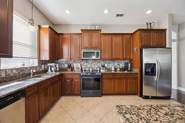 a kitchen with stainless steel appliances granite countertop table chairs sink and window