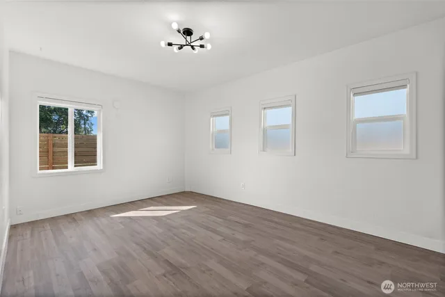 a view of an empty room with a window and wooden floor