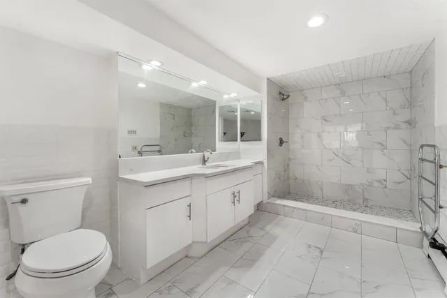 a bathroom with a double vanity sink toilet and shower