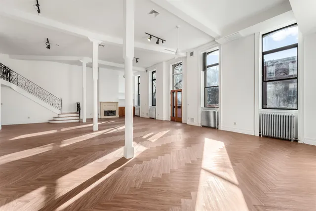 a view of a big room with wooden floor and windows