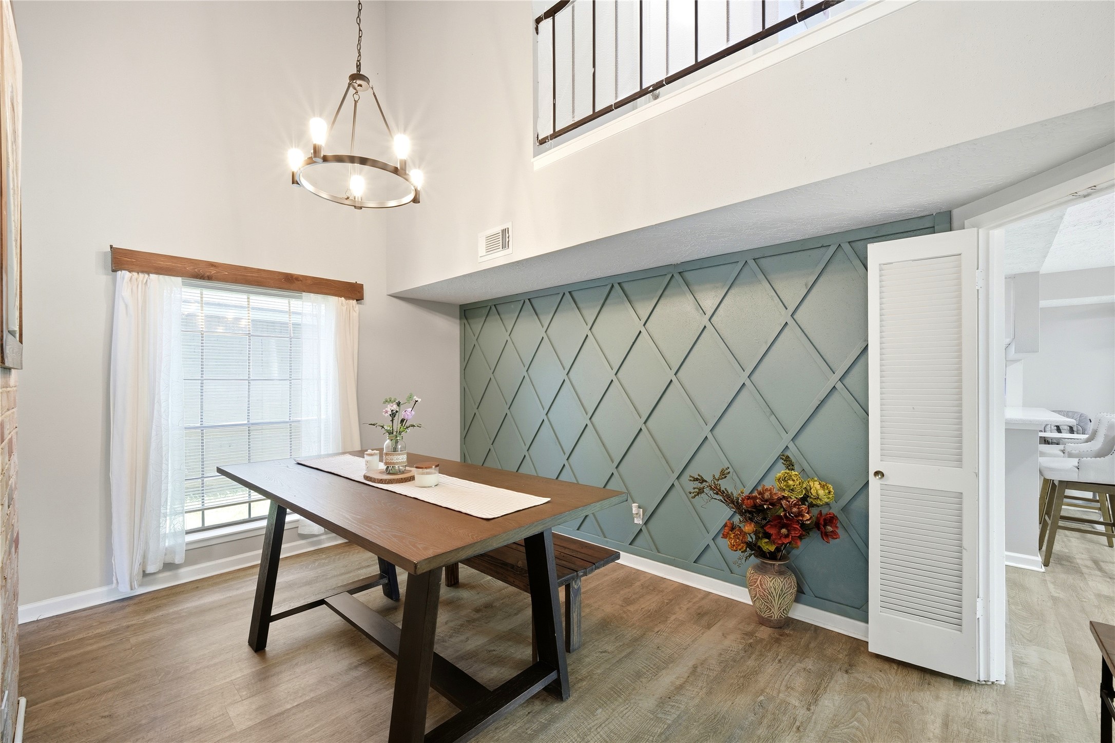 4718 Temple Bell Drive Spring, TX 77388 - Photo 12 of 50 A bright dining area with vaulted ceilings features a stylish accent wall and modern chandelier. Large windows provide natural light, complementing the wood-look flooring and open layout.
