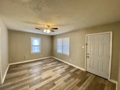a view of an empty room with window and hardwood floor