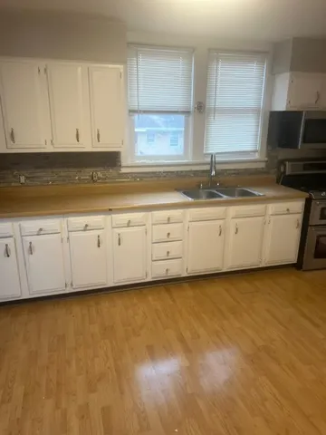 a kitchen with granite countertop a sink a stove top oven a counter space and cabinets