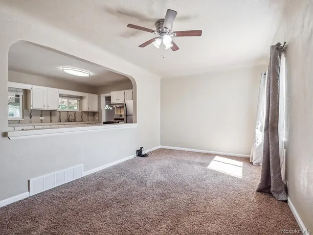 a view of an empty room with kitchen view