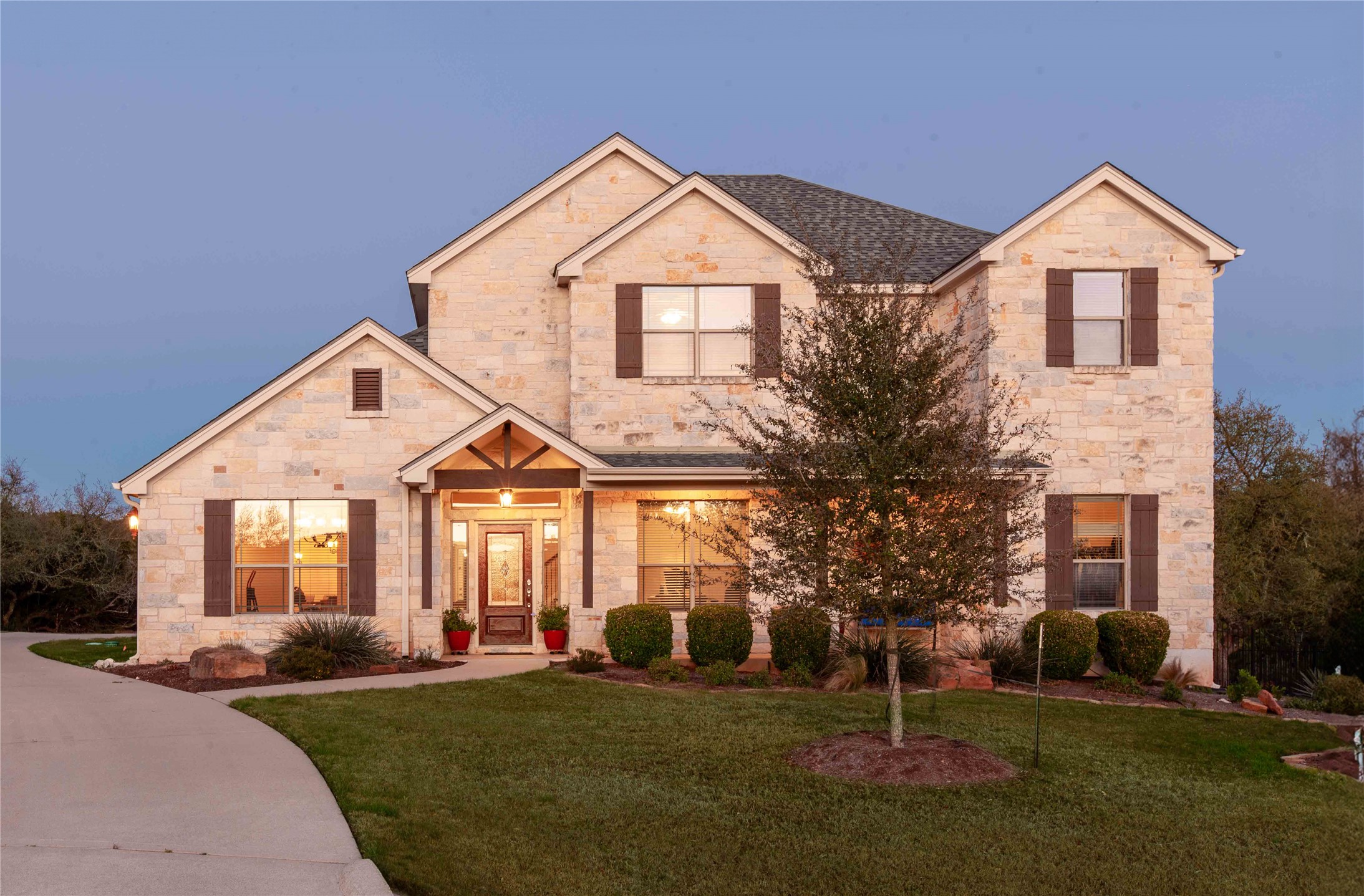 1432 Tom Sawyer Road Austin, TX 78737 - Photo 1 of 33 A stone-clad residence with welcoming porch lighting and meticulous landscaping beckons at twilight.