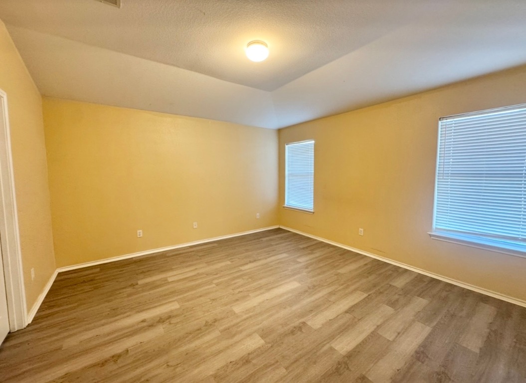 12809 Wood Lily Trail Elgin, TX 78621 - Photo 12 of 26 Spare room with light wood-type flooring, vaulted ceiling, and a textured ceiling