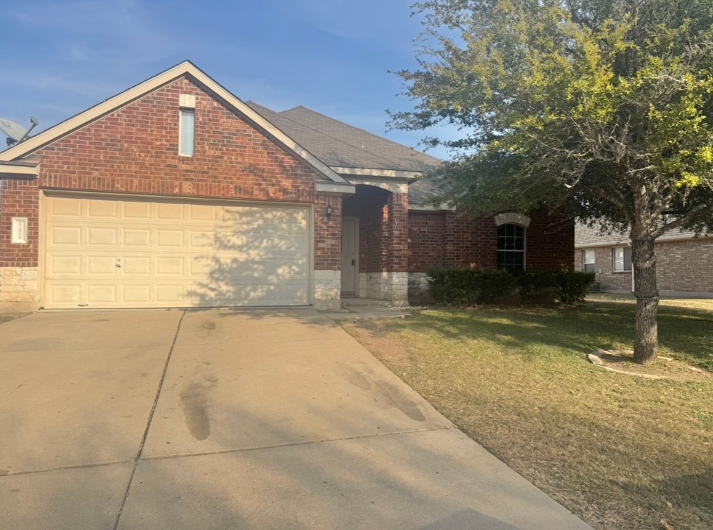 12809 Wood Lily Trail Elgin, TX 78621 - Photo 2 of 26 View of front of home with brick siding, concrete driveway, a front lawn, and a garage