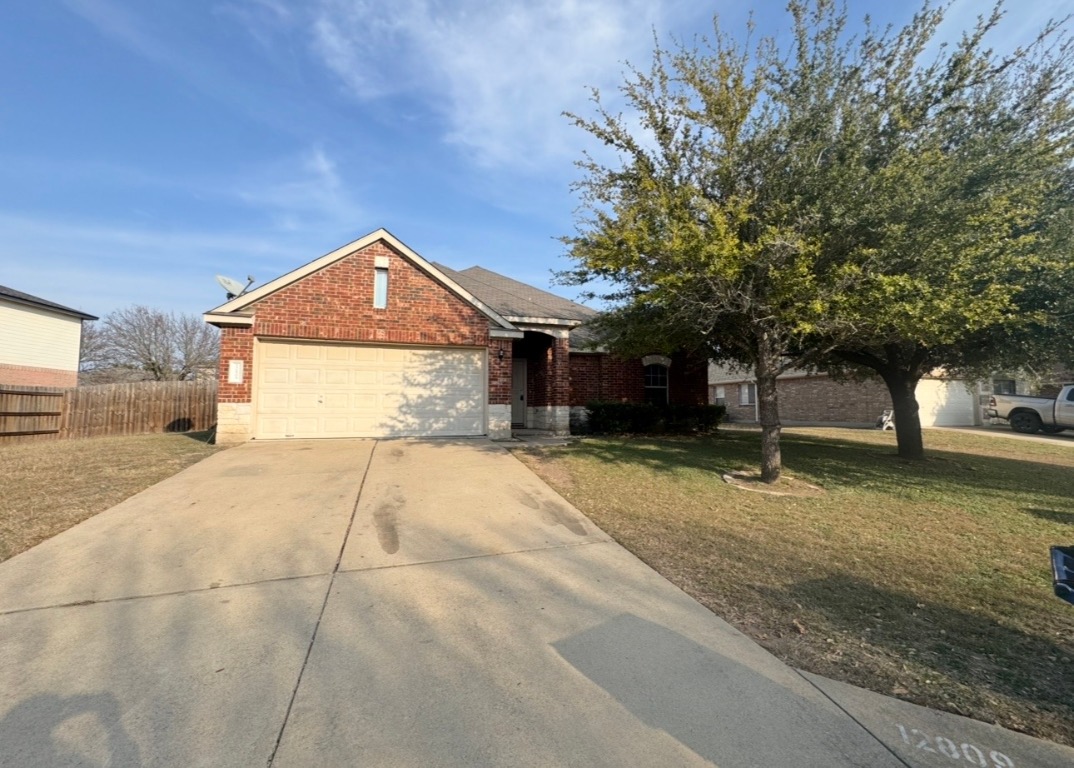 12809 Wood Lily Trail Elgin, TX 78621 - Photo 3 of 26 View of front of house featuring brick siding, concrete driveway, and an attached garage