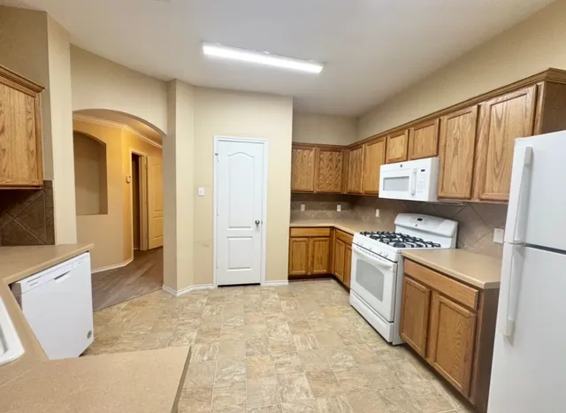 a kitchen with granite countertop a refrigerator stove top oven and sink