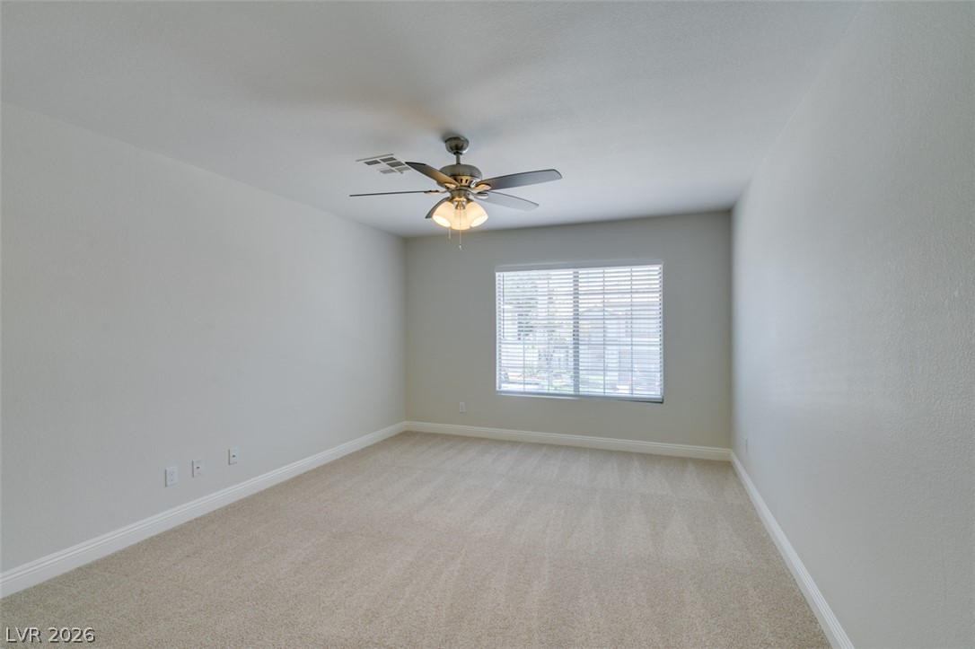 200 Luninborg Street Henderson, NV 89074 - Photo 30 of 40 An airy bedroom with soft carpeting and a ceiling fan, offering a serene personal haven.