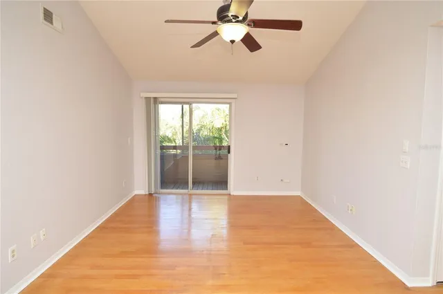 an empty room with wooden floor fan and windows