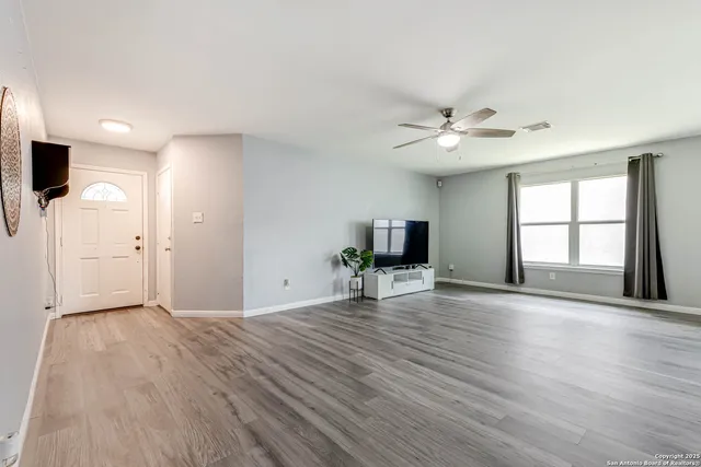 a view of an empty room with window and wooden floor