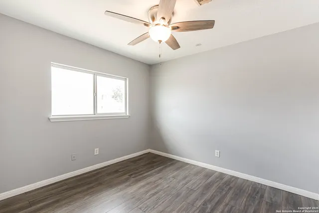 an empty room with a window and a fan