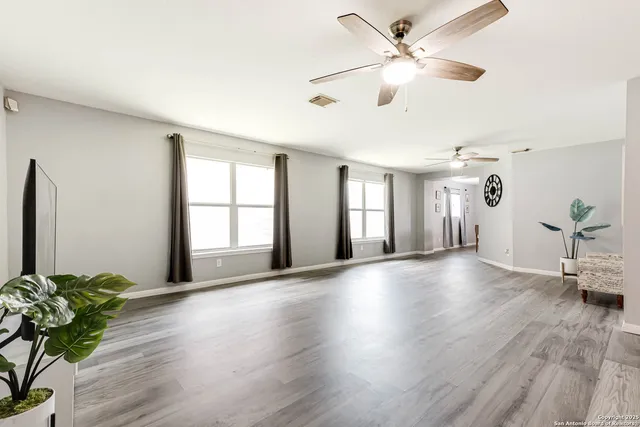 a view of an empty room with window and wooden floor