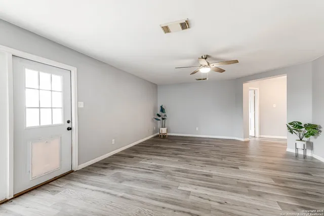 a view of an empty room with a window and wooden floor