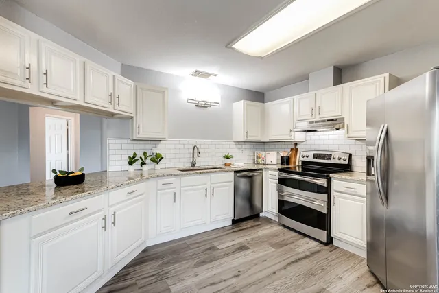 a kitchen with white cabinets stainless steel appliances and a sink