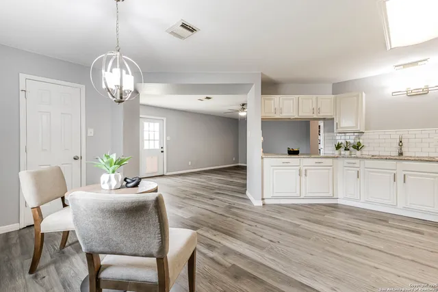 a dining room with wooden floor a chandelier a wooden table and chairs