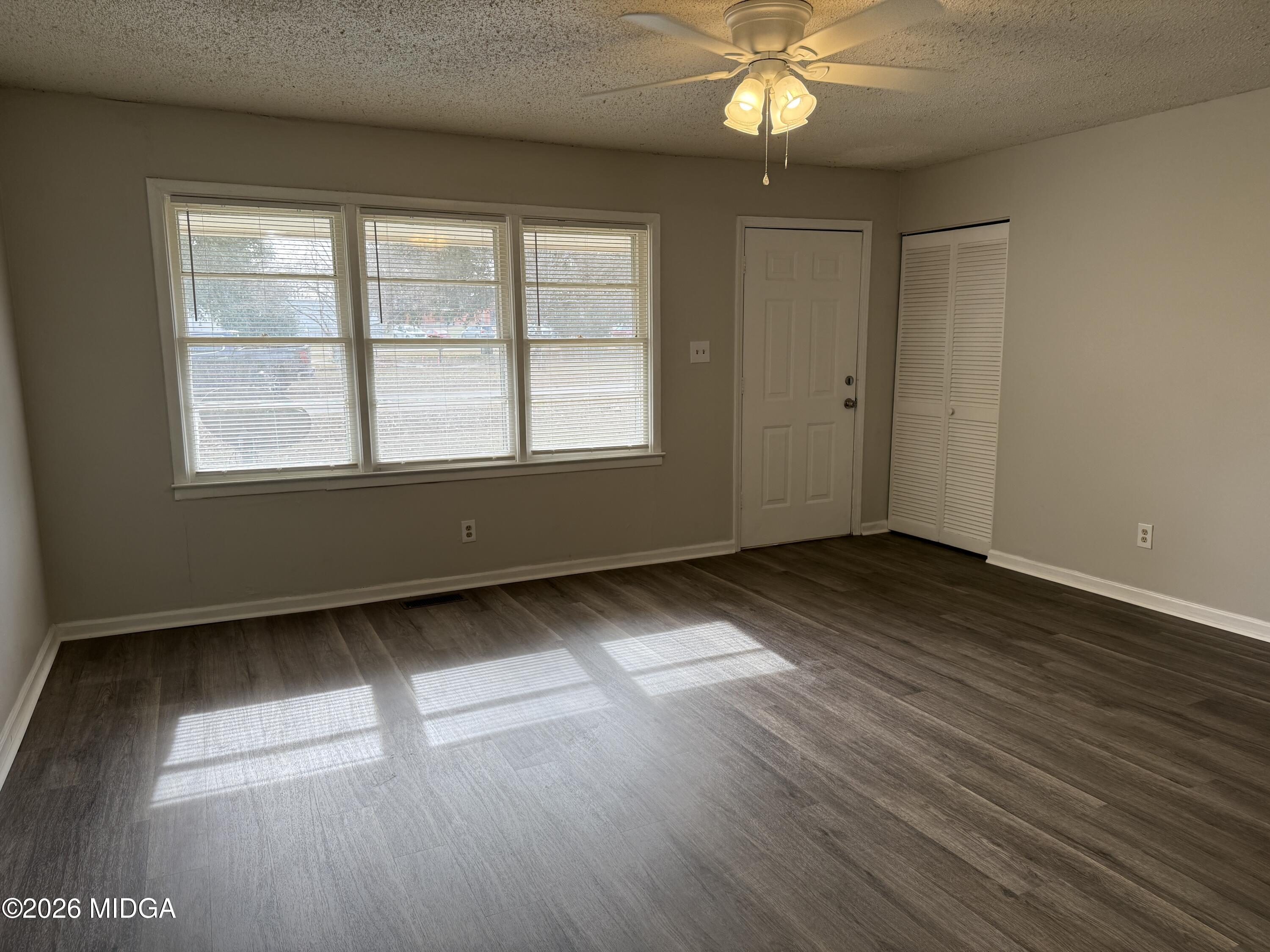 107 Miller Court Centerville, GA 31028 - Photo 2 of 16 an empty room with wooden floor fan and windows